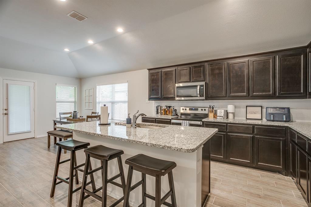 9912 Mescalbean Boulevard Crowley, TX 76036 - Photo 2 of 23 a kitchen with stainless steel appliances granite countertop a stove top oven a sink dishwasher a dining table and chairs