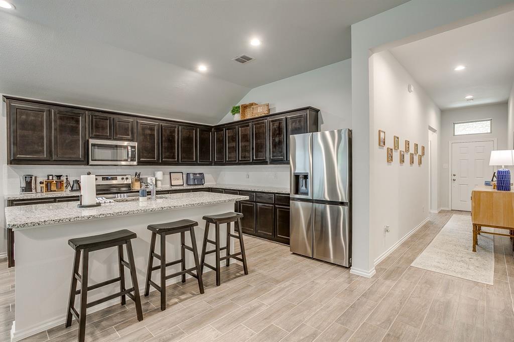 9912 Mescalbean Boulevard Crowley, TX 76036 - Photo 9 of 23 a kitchen with stainless steel appliances granite countertop a refrigerator a stove a sink a dining table and chairs