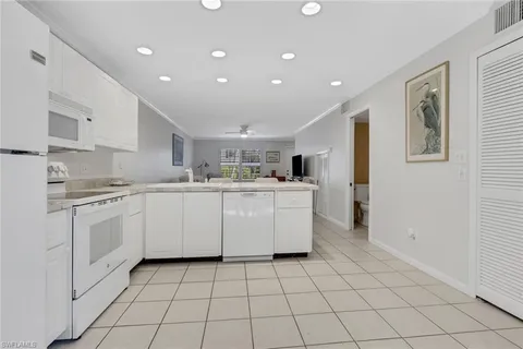 a kitchen with white cabinets a sink and white appliances