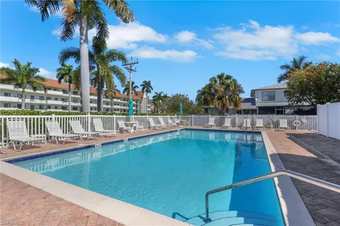a view of a swimming pool with a lawn chairs under an umbrella