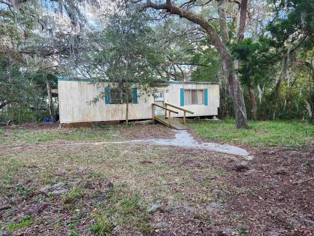 a view of a house with a yard and large trees