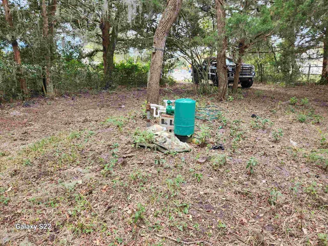 a view of a fire pit with large trees and wooden fence