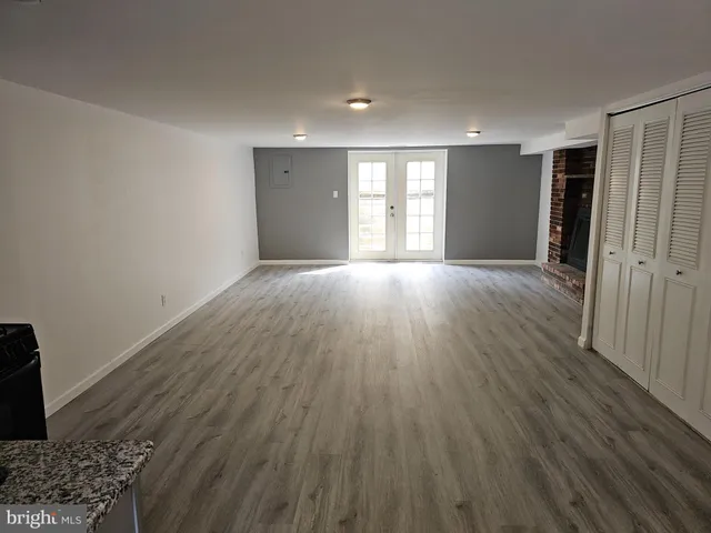 a view of an empty room with wooden floor and a fireplace