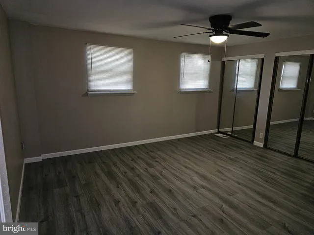 an empty room with wooden floor closet and windows
