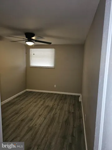 an empty room with wooden floor closet and windows