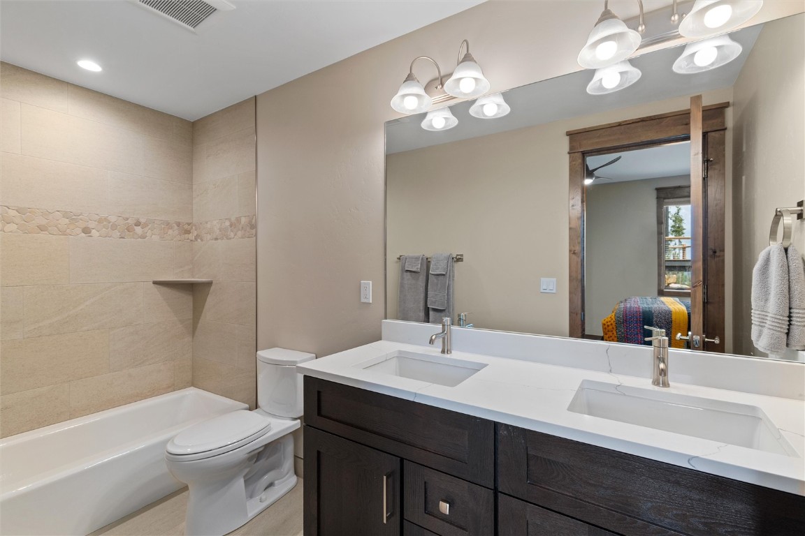 344 Angler Mountain Ranch Road Silverthorne, CO 80498 - Photo 22 of 32 a bathroom with a sink a toilet a mirror a vanity and bathtub