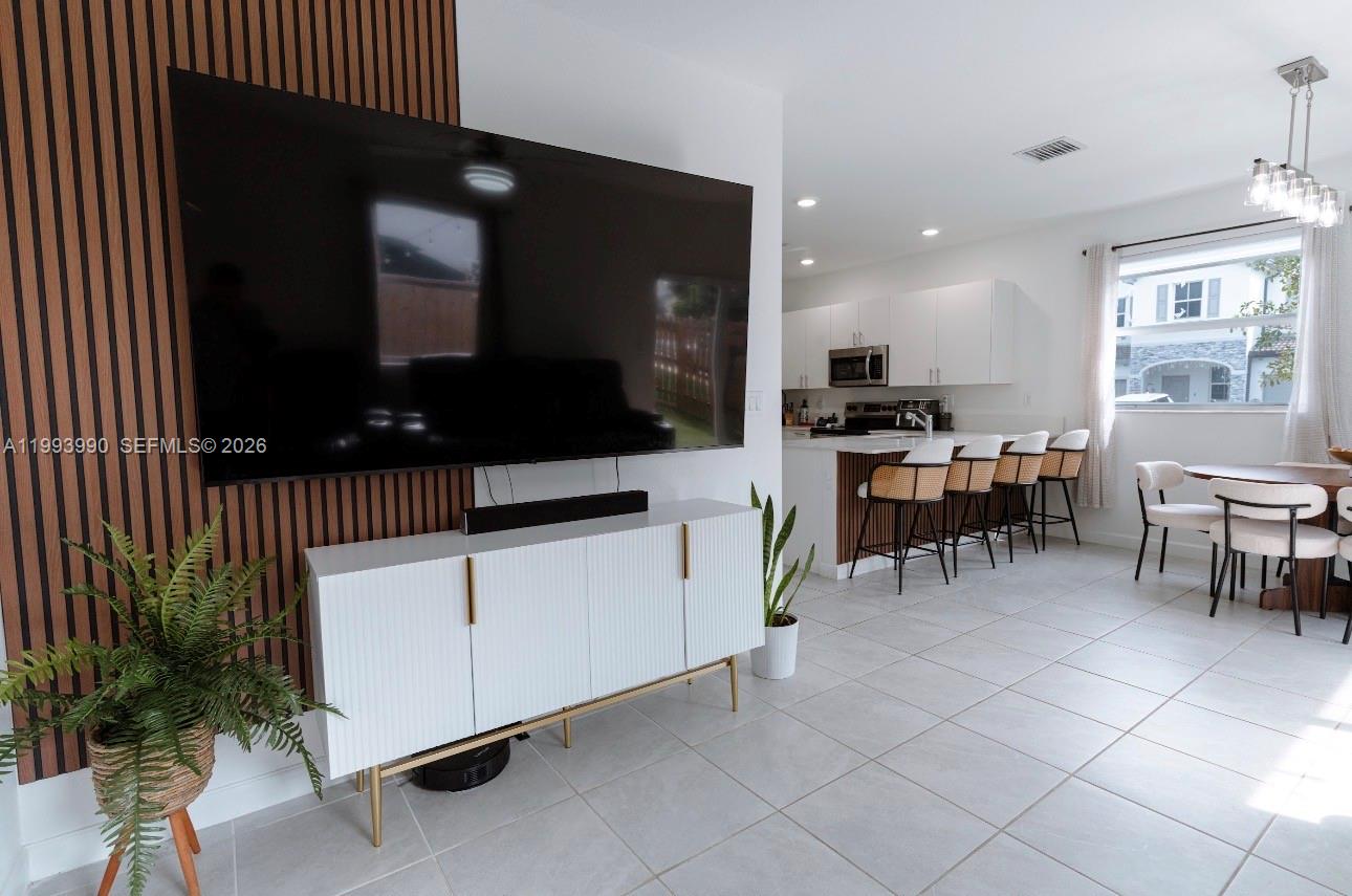 16222 Southwest 290th Terrace, Unit 16222 Homestead, FL 33033 - Photo 11 of 38 a living room with furniture a flat screen tv and kitchen view