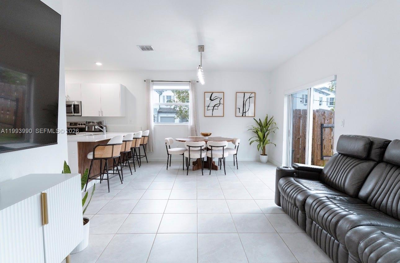 16222 Southwest 290th Terrace, Unit 16222 Homestead, FL 33033 - Photo 13 of 38 a living room with furniture a dining table and a fireplace