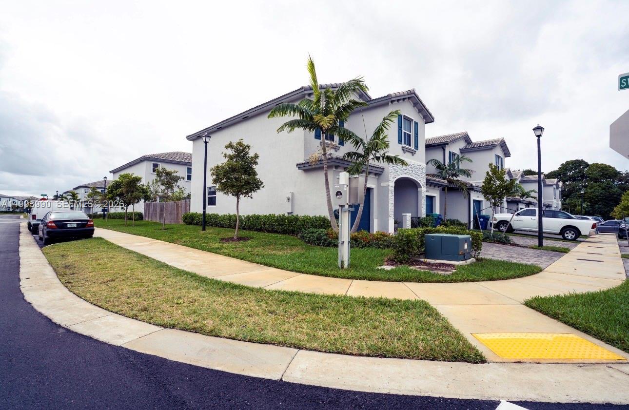 16222 Southwest 290th Terrace, Unit 16222 Homestead, FL 33033 - Photo 34 of 38 a view of a white house with a yard and potted plants
