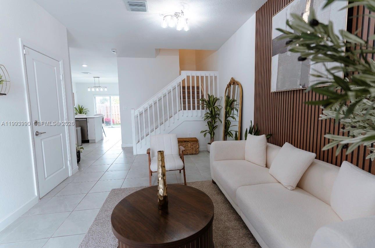 16222 Southwest 290th Terrace, Unit 16222 Homestead, FL 33033 - Photo 7 of 38 a living room with furniture and a chandelier