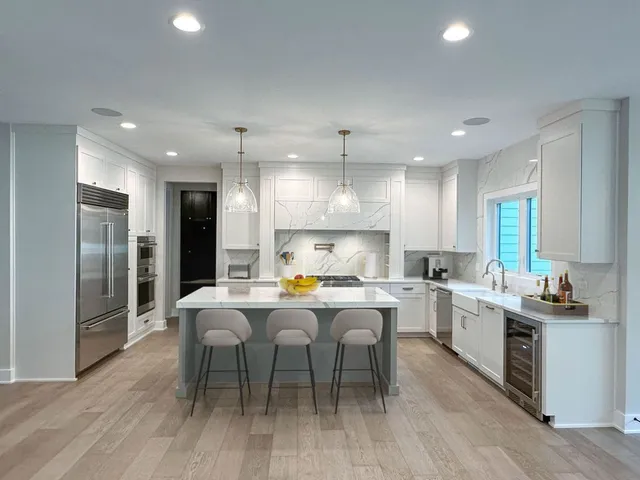 a kitchen with stainless steel appliances a dining table chairs stove refrigerator and cabinets