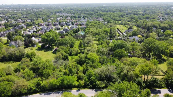 an aerial view of residential house with outdoor space and trees all around