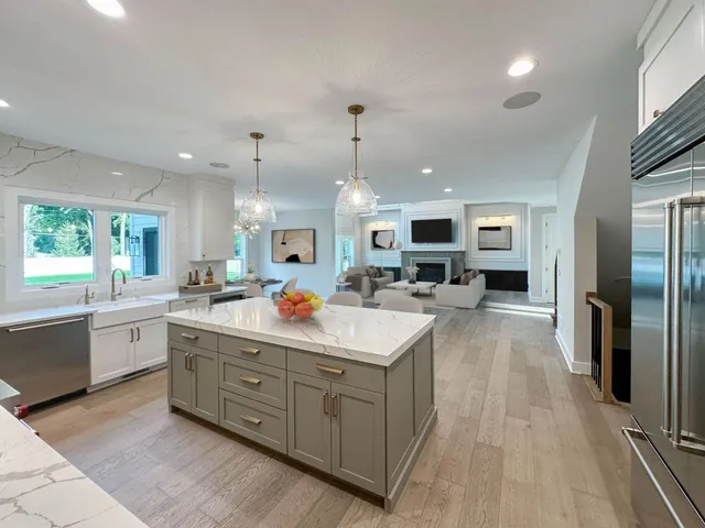 a large kitchen with kitchen island a large counter top stainless steel appliances a sink and living room view