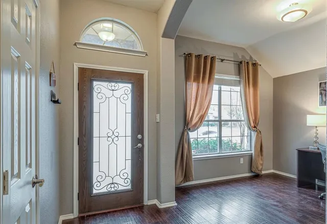 an empty room with wooden floor mirror and windows