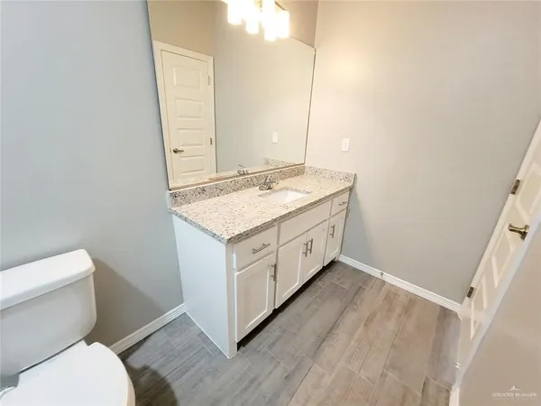 a bathroom with a granite countertop toilet sink and mirror