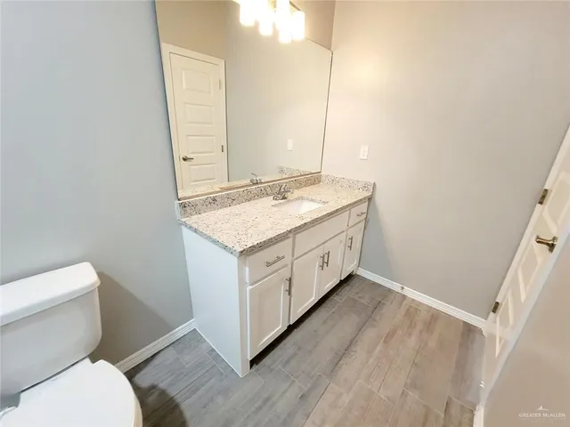 a bathroom with a granite countertop toilet sink and mirror