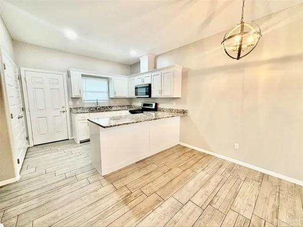 a kitchen with stainless steel appliances granite countertop a sink a stove a refrigerator a microwave oven with white cabinets