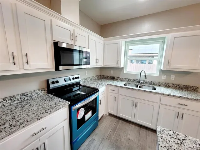a kitchen with granite countertop a sink a stove and cabinets