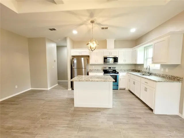 a large kitchen with granite countertop a sink cabinets and stainless steel appliances