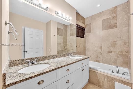 4025 Southwest 10th Street Miami, FL 33134 - Photo 25 of 41 a bathroom with a granite countertop double vanity sink a mirror and a bathtub