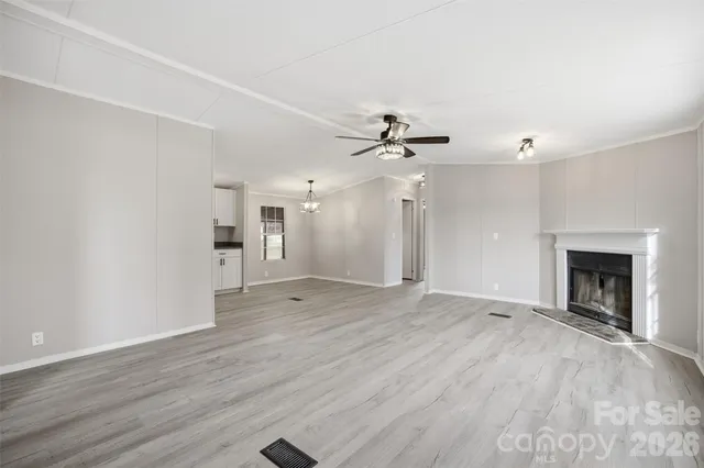 a view of an empty room with wooden floor fireplace and a window