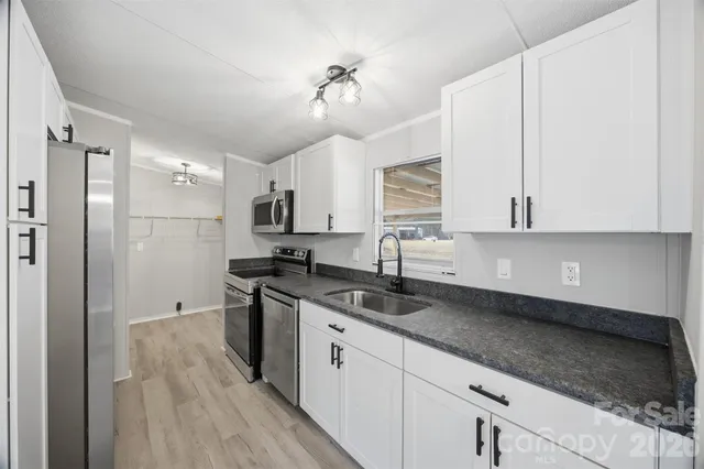 a kitchen with stainless steel appliances granite countertop a sink a stove and a refrigerator