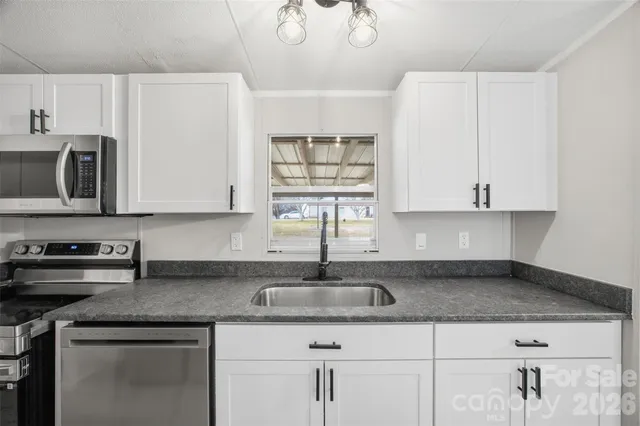 a kitchen with stainless steel appliances granite countertop a sink a stove and cabinets