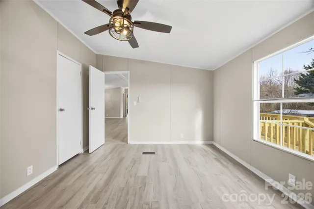 a view of empty room with wooden floor and fan