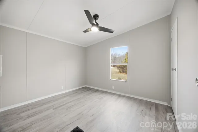 an empty room with wooden floor ceiling fan and windows