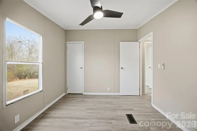 a view of an empty room with a window and wooden floor