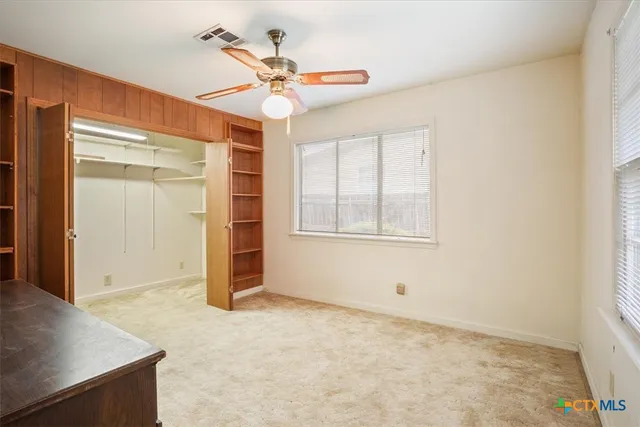 an empty room with closet and windows