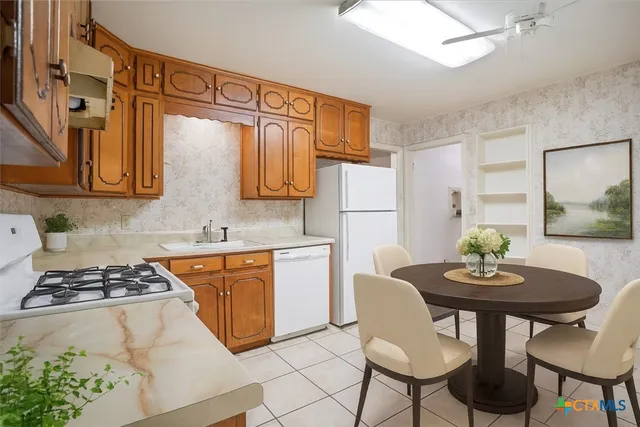 a kitchen with stainless steel appliances granite countertop a table chairs a stove a refrigerator and a sink