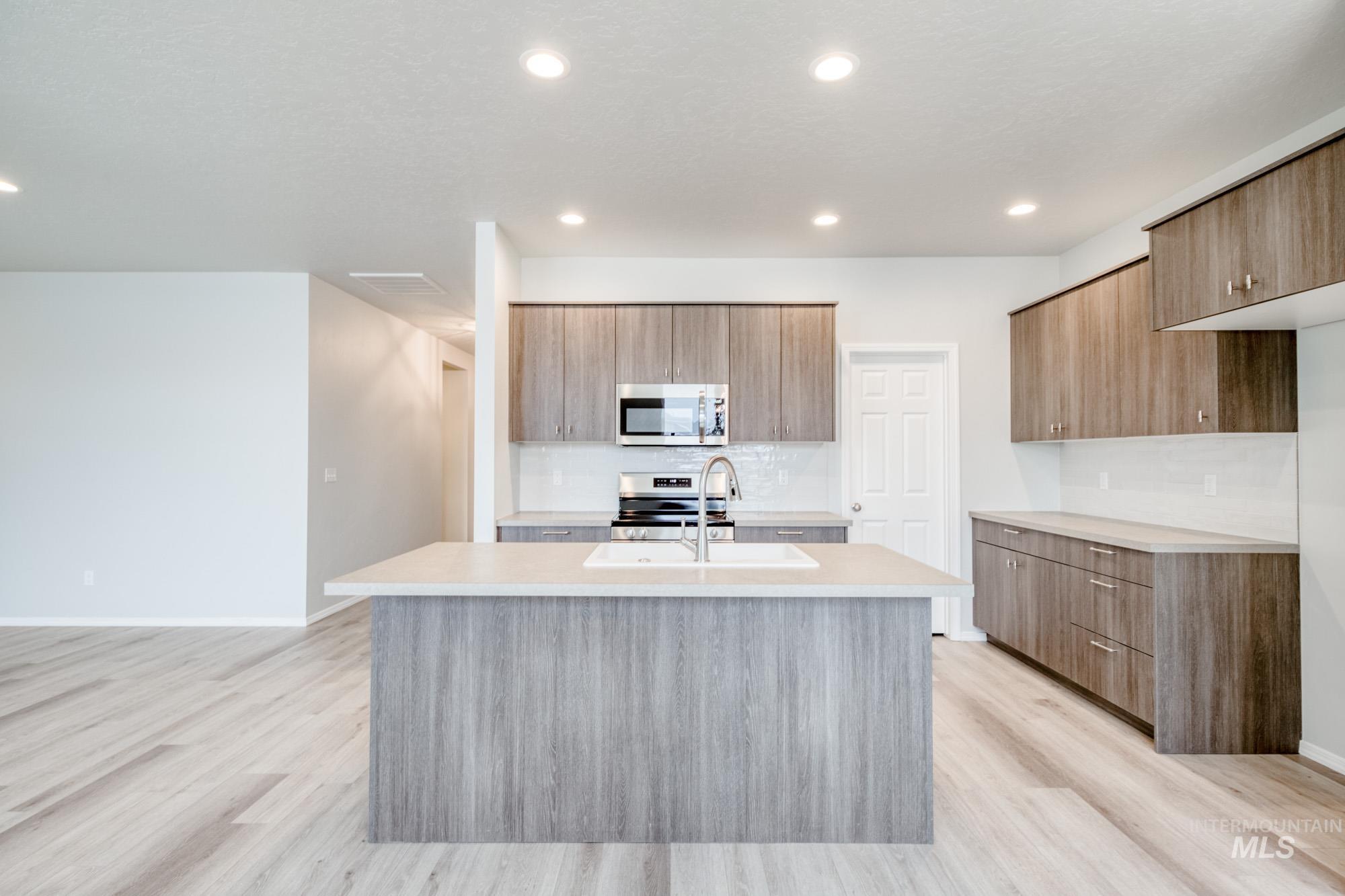 13696 Nisene Street Caldwell, ID 83607 - Photo 3 of 24 Kitchen featuring modern cabinets, appliances with stainless steel finishes, a center island with sink, backsplash, and light wood-type flooring