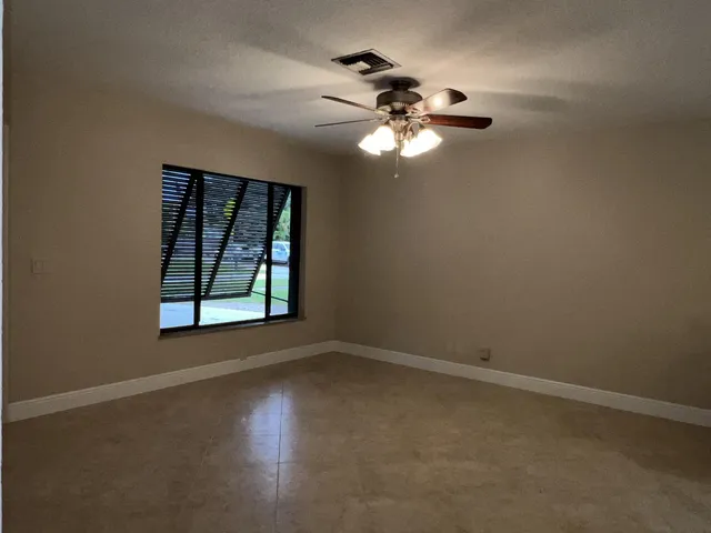 an empty room with windows and fan