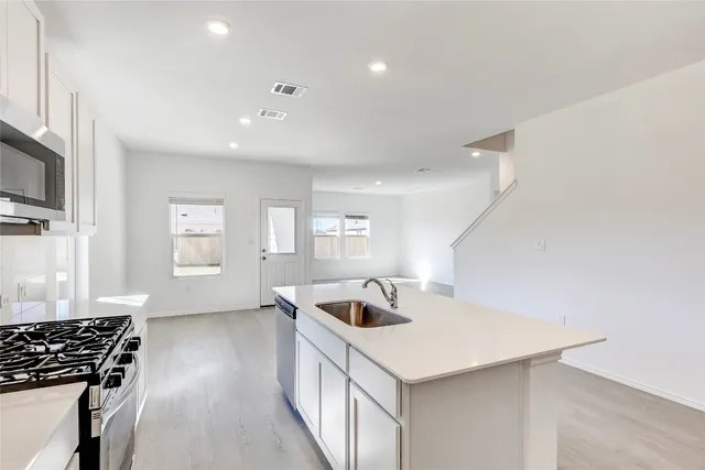 a kitchen with a sink a counter top space appliances and cabinets