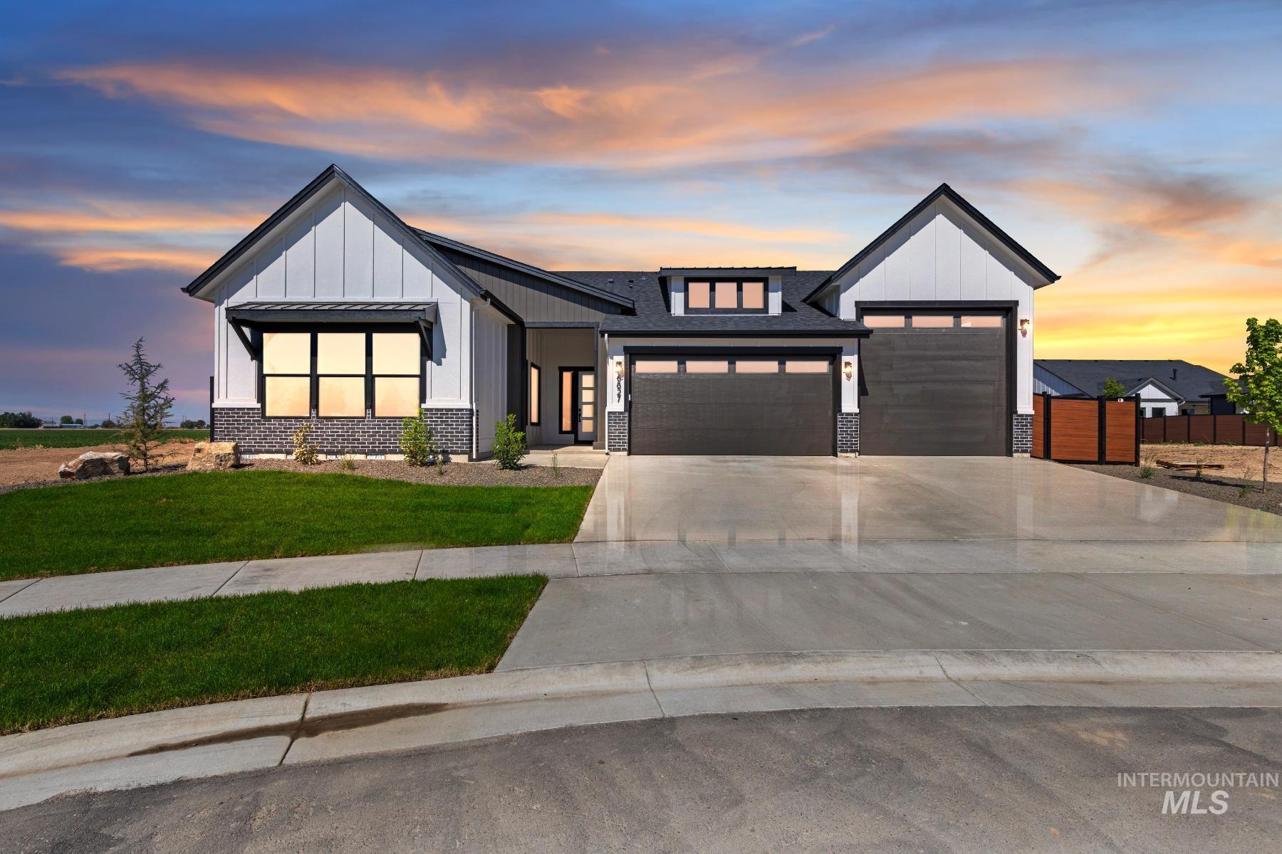 Modern farmhouse style home with board and batten siding, a garage, driveway, and stone siding