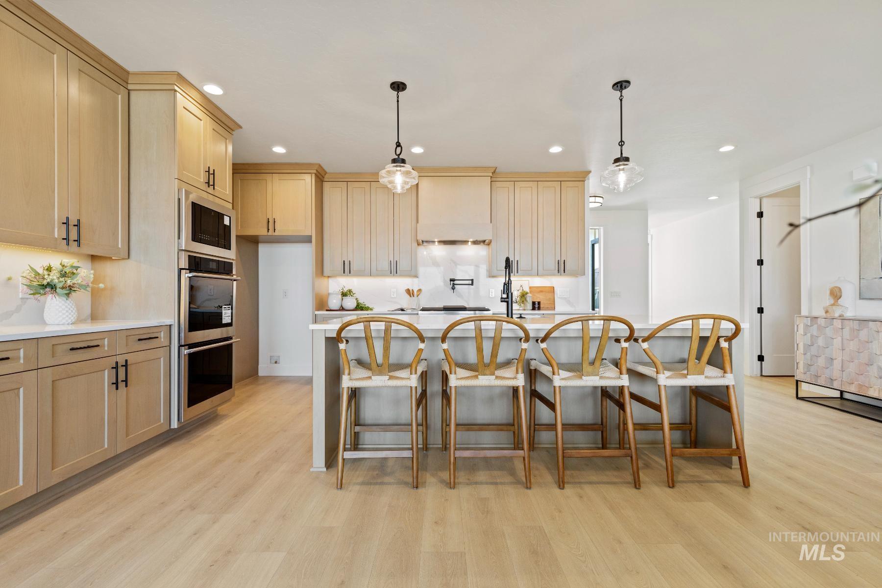 8650 West Inspirado Street Meridian, ID 83646 - Photo 16 of 30 Kitchen with decorative light fixtures, a breakfast bar, light brown cabinets, appliances with stainless steel finishes, and recessed lighting