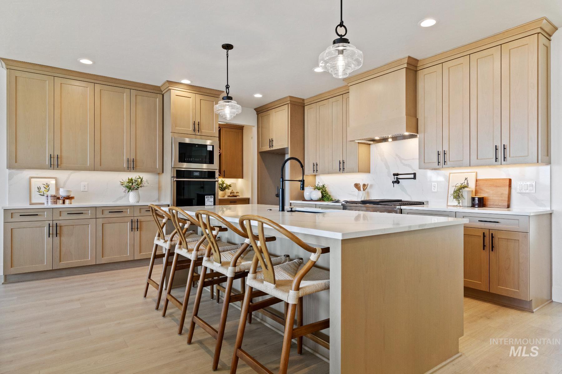 8650 West Inspirado Street Meridian, ID 83646 - Photo 17 of 30 Kitchen featuring light wood-type flooring, a breakfast bar area, light stone countertops, stainless steel appliances, and recessed lighting