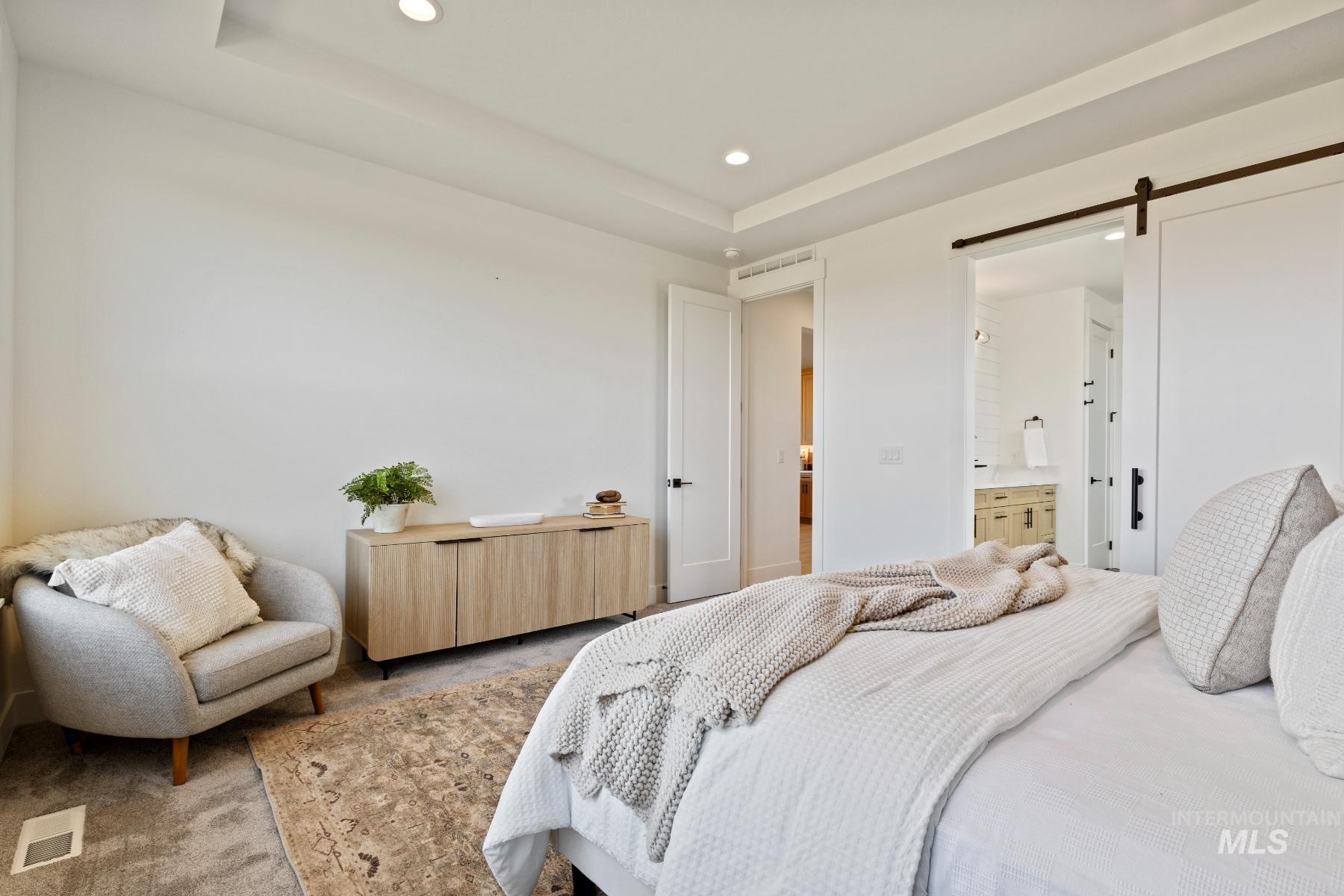 8650 West Inspirado Street Meridian, ID 83646 - Photo 23 of 30 Carpeted bedroom with a barn door, recessed lighting, a tray ceiling, and connected bathroom