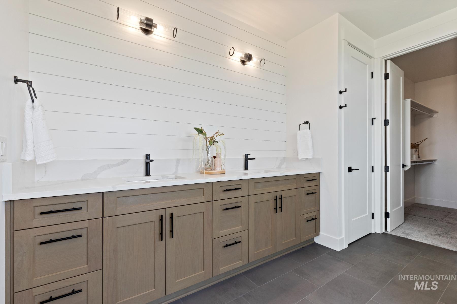 8650 West Inspirado Street Meridian, ID 83646 - Photo 27 of 30 Bathroom featuring double vanity, dark tile patterned floors, and wood walls