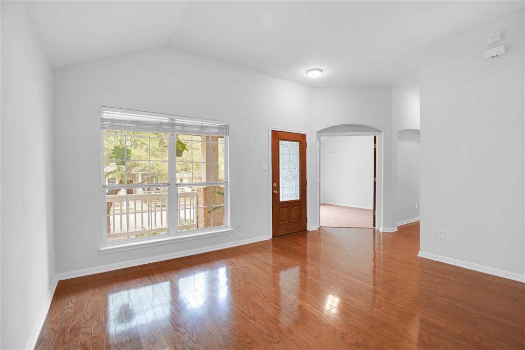 281 Hutton Kyle, TX 78640 - Photo 13 of 37 Rich hardwood flooring reflects light from a broad window, complementing the airy vaulted ceilings.