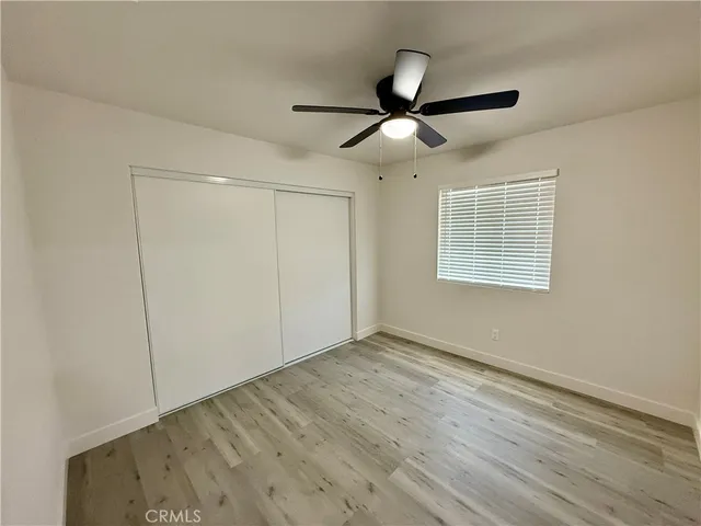 a view of an empty room with wooden floor and a ceiling fan