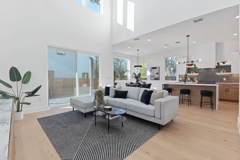 a living room with furniture kitchen view and a large window