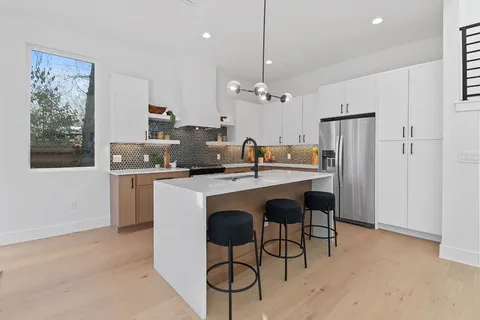 a kitchen with kitchen island a dining table chairs cabinets and stainless steel appliances