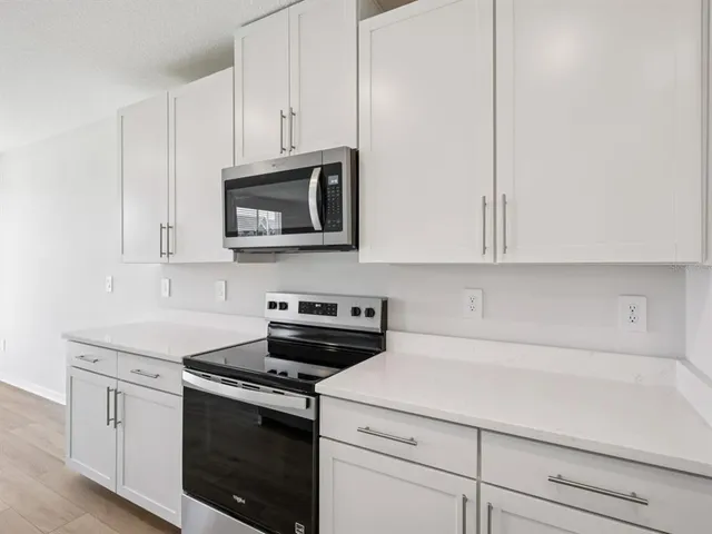 a kitchen with stainless steel appliances granite countertop white cabinets and a stove a oven with white countertops