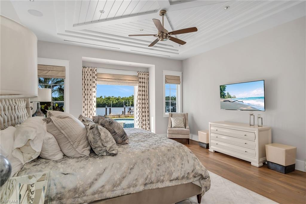 185 15th Street South Naples, FL 34102 - Photo 13 of 49 a bedroom with a bed a chandelier and a flat tv screen