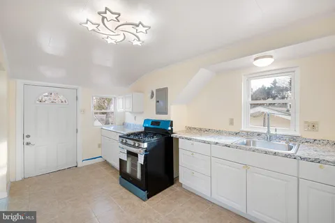 a kitchen with stainless steel appliances granite countertop a stove a sink and a refrigerator with white cabinets