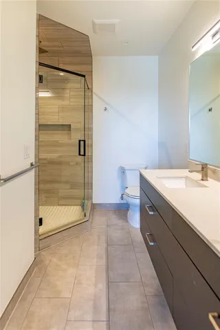 a bathroom with a granite countertop sink a toilet and shower