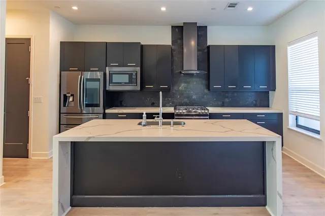 a kitchen with kitchen island stainless steel appliances a sink and a refrigerator