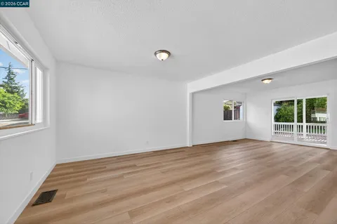 an empty room with a wooden floor and windows
